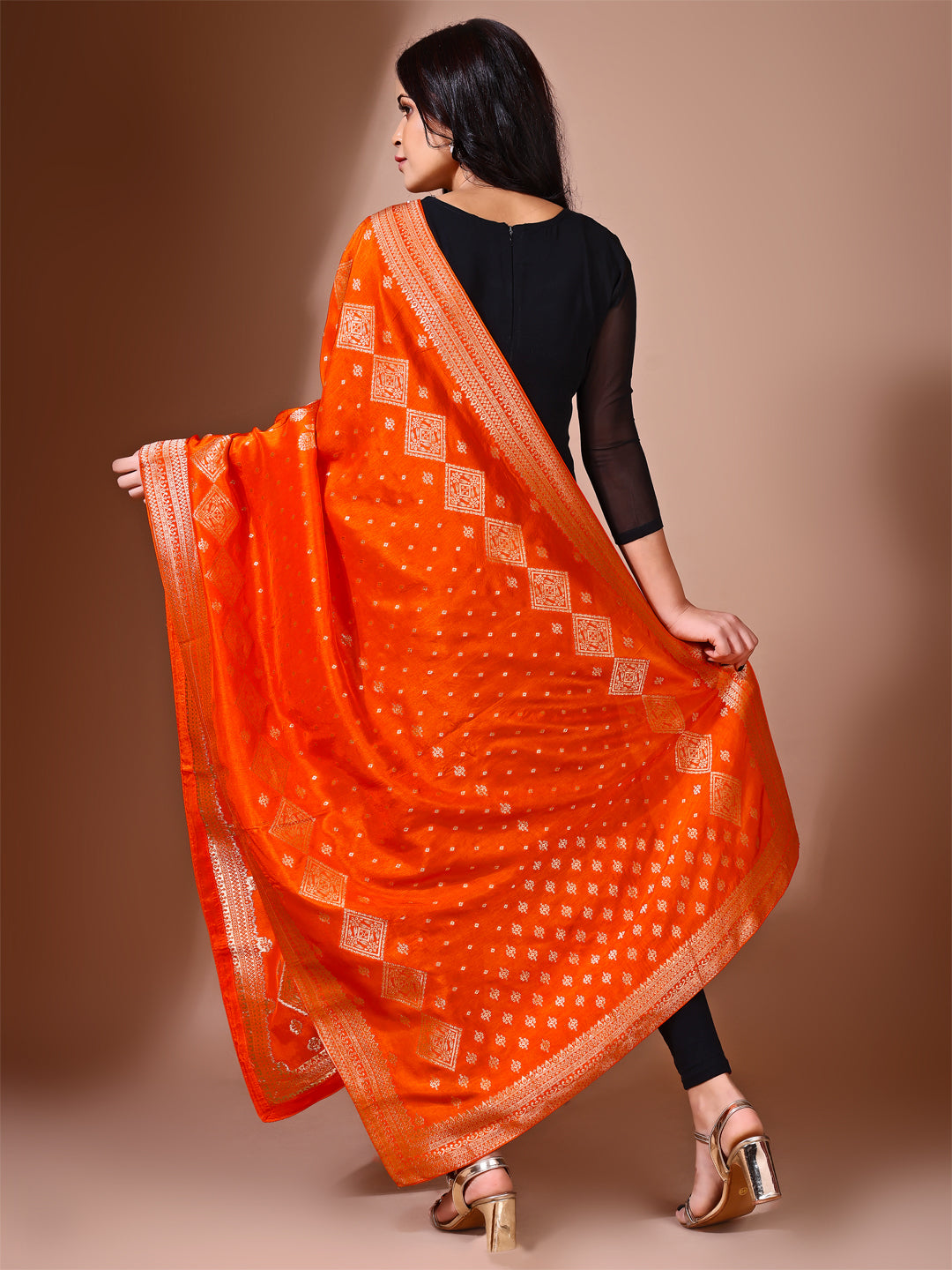 Model in a fancy pose wearing a orange Banarasi bridal dupatta, ideal for wedding wear.